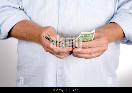 Mature man counts his cash money which are US dollar bills. Stock Photo