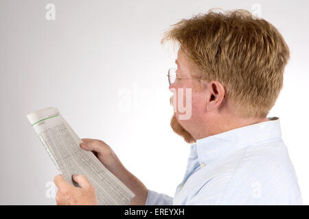 Mature male reads the stock market report in the newspaper to glean financial information and improve his investments. Stock Photo