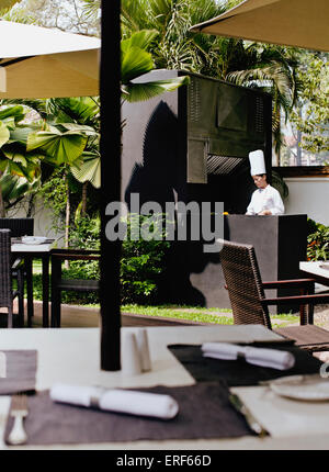 Young Asian female chef behind the grill at the Poolside BBQ restaurant, La Residence d'Angkor, Siem Reap, Cambodia. Stock Photo