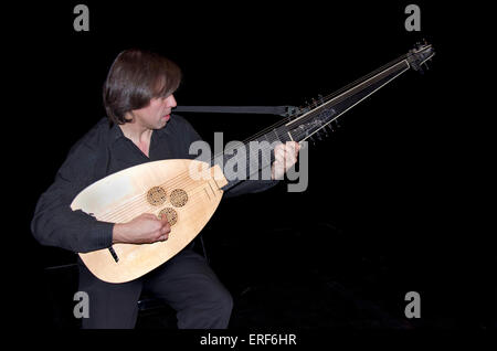 Musician playing a theorbo,a long-necked lute with a second pegbox.  Originally a bass lute adapted with a neck extension to Stock Photo