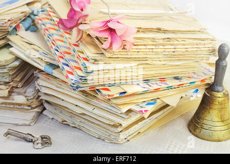 The memory of the past. Stacks of old letters, vintage artificial flowers, key and bell. Stock Photo