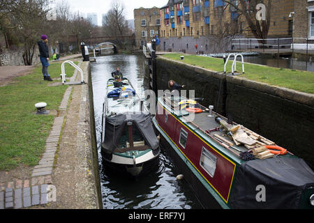 Narrowboat entering a lock on Regents Canal in East London, UK. Regent's Canal crosses an area just north of central London. It provides a link from the Paddington Arm of the Grand Union Canal in the west, to Limehouse and the River Thames in east London. The canal is 13.8 kilometres (8.6 miles) long. Stock Photo