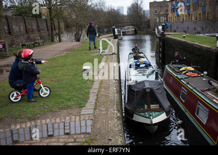 Narrowboat entering a lock on Regents Canal in East London, UK. Regent's Canal crosses an area just north of central London. It provides a link from the Paddington Arm of the Grand Union Canal in the west, to Limehouse and the River Thames in east London. The canal is 13.8 kilometres (8.6 miles) long. Stock Photo