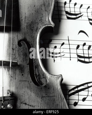 Violin close up showing  F-hole. Instrument is laying on musical score backdrop.