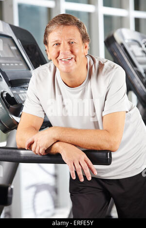 Active smiling senior man on treadmill in fitness center Stock Photo