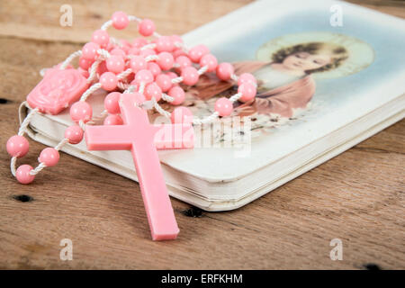 Pink rosary over a religious book on table Stock Photo