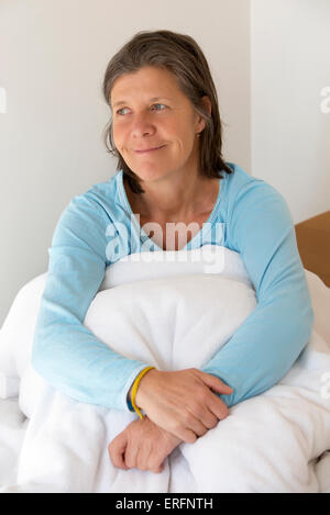 older woman sitting in bed and looking sad Stock Photo - Alamy