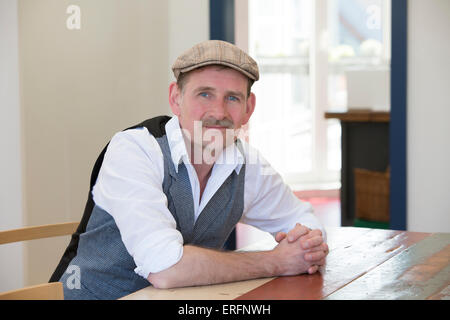 man in his 50's sitting at table and smiles at camera Stock Photo