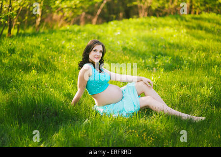 Young happy woman in expectation of baby. Female hands holding pregnant belly. Beautiful mother enjoying nature. Pregnant woman Stock Photo