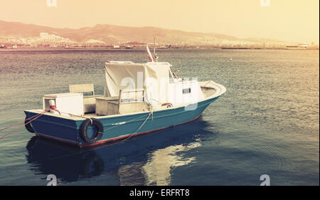 Old wooden pleasure boat anchored in Izmir bay, Turkey. Vintage stylized photo with yellow tonal correction photo filter, old st Stock Photo