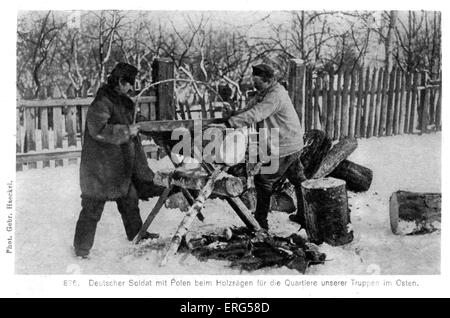 German Occupation on the Eastern Front in World War I. A German soldier and with a Polish man saw wood for the German barracks in the East. There is snow on the ground. Caption reads: 'Deutscher Soldat mit Polen beim Holzsägen für die Quartiere unserer Truppen im Osten.'/ 'A German soldier and a Polish man saw wood for our soldiers' quarters in the East.' (probably modern day Poland) From 'Unter deutscher Besatzung' / 'Under German Occupation' collection Stock Photo