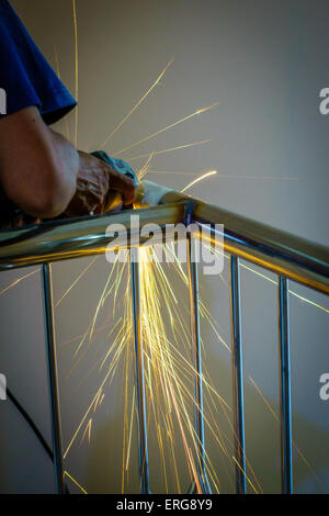 A man grinding or cutting or welding stainless steel/iron bar using a grinder Stock Photo
