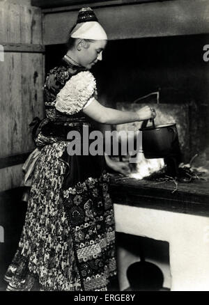 Farmer 's Kitchen in Mezőkövesd, Hungary . Woman in traditional dress cooks at stove over the fire. Town in Borsod-Abaúj-Zemplén county, Northern Hungary. C. 1933. Stock Photo