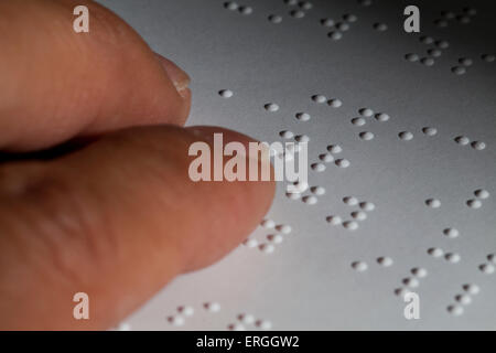 Man's fingers reading braille text on paper - USA Stock Photo