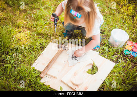 Little girl making Wooden birdhouse Stock Photo