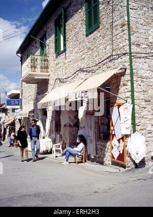Couple walking past a lace shop in the town centre, Pano Lefkara, Cyprus. Stock Photo