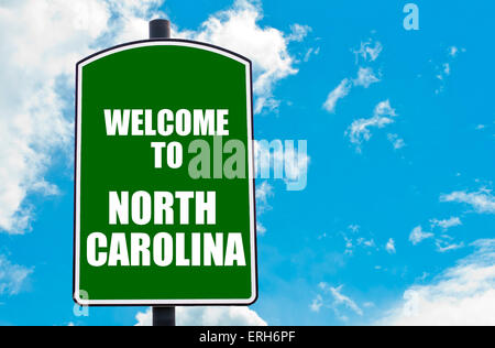 Green road sign with greeting message Welcome to NORTH CAROLINA isolated over clear blue sky background Stock Photo