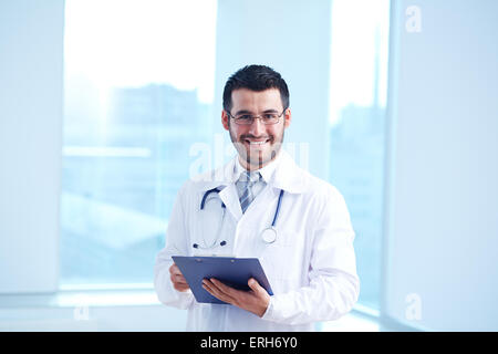 Smiling doctor with clipboard and stethoscope looking at camera Stock Photo