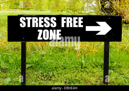 STRESS FREE ZONE written on directional black metal sign with arrow pointing to the right against natural green background. Stock Photo