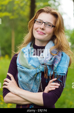 Portrait of young serious woman  standing at summer green park Stock Photo