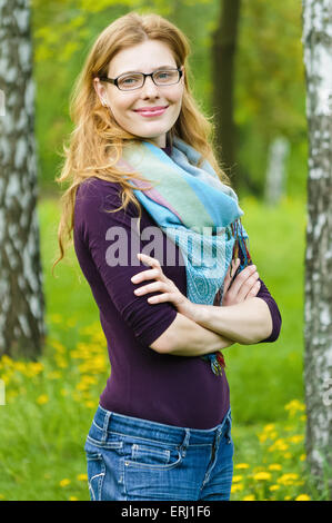 Portrait of young serious woman  standing at summer green park Stock Photo