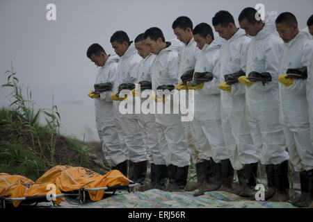 Jianli, China. 03rd June, 2015. Rescuers  stand in silent tribute to the bodies of a victim fund from the sank ship 'Eastern Star' on the bank of the Yangtze River in Jianli county, Hubei province, central China, 3th June 2015. The ship, Carrying 406 passengers, five travel agency workers and 47 crew members,sank at around 9:28 p.m. (1328 GMT) on Monday,  according to the Xinhua News Agencey Said. Credit:  Panda Eye/Alamy Live News Stock Photo
