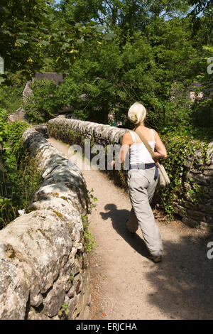 UK, England, Derbyshire, Dovedale,  visitor crossing Viators old packhorse bridge over River Dove to Milldale Stock Photo