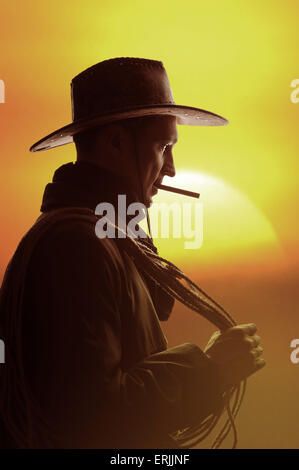 cowboy in hat with cigar and lasso silhouette Stock Photo