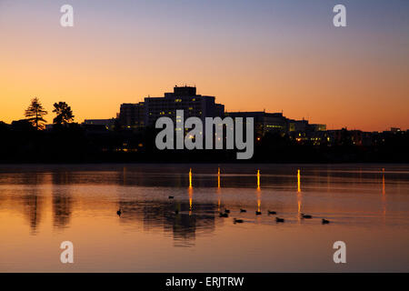 Waikato Hospital reflected in Lake Rotoroa at dawn, Hamilton, Waikato, North Island, New Zealand Stock Photo