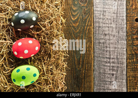 Three Easter eggs and hay on wooden background Stock Photo