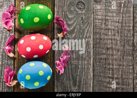 Three Easter eggs and flowers on wooden background Stock Photo