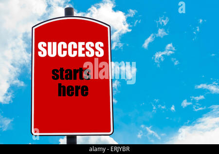 Success Starts Here motivational quote written on red road sign isolated over clear blue sky background. Concept image with available copy space Stock Photo