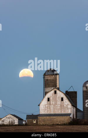 Partial lunar eclipse over farm buildings near Shakopee, Minnesota. Stock Photo