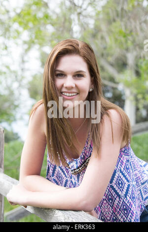 Portrait of a teenage girl in jeans and a crop top leaning on a wooden fence Stock Photo