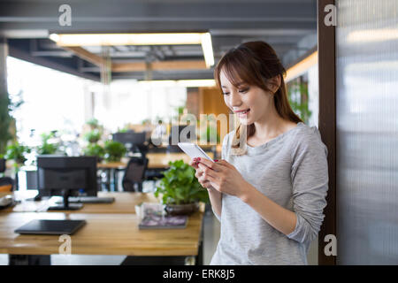 Young woman using smart phone in office Stock Photo