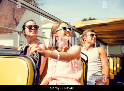 group of smiling friends traveling by tour bus Stock Photo