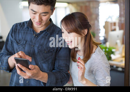 IT workers looking at smart phone in office Stock Photo
