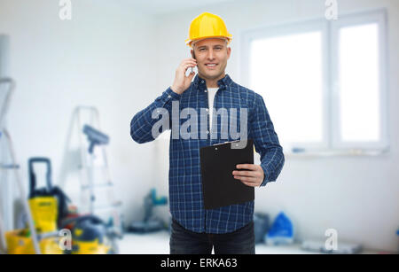 smiling builder in helmet calling on smartphone Stock Photo