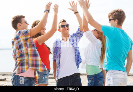 group of smiling friends making high five outdoors Stock Photo