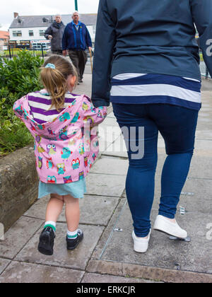 Rear view of a mother holding the hand of a young girl going home from school Stock Photo