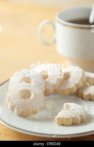 Saucer with nibbled italian canestrelli cookies near a cup of black tea. Stock Photo