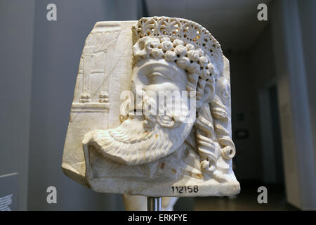 Roman relief. Mask of a deity wearing a crown in archaizing style and a tripod in the background. 1st c. AD. Rome. Stock Photo