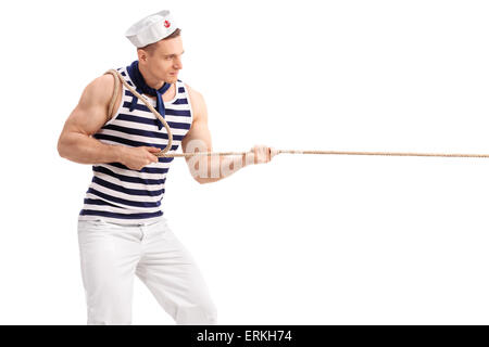 Studio shot of a young man in sailor uniform pulling a rope isolated on white background Stock Photo