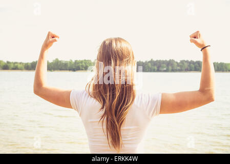 Girl is pointing her hands towards the sky in the manner of success, she's standing in the water. Stock Photo