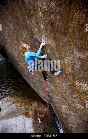 Woman climbing a small crack above her belay partner and a river in Yosemite National Park, California (high angle view). Stock Photo