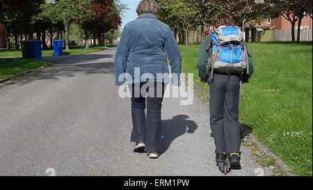 Young boy going to school on scooter with grandmother Stock Photo