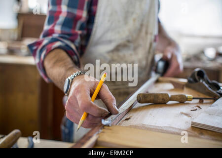 An antique furniture restorer measuring a piece of wood. Stock Photo