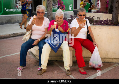 Three elderly women sitting on couch and eating ice cream Stock Photo
