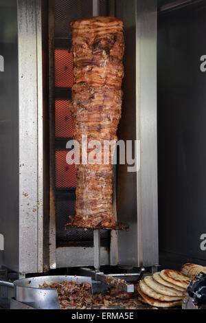 Pork gyros on vertical broiler rotisserie machine and grilled pita souvlaki bread. Traditional greek fast food. Stock Photo