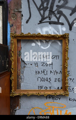 Vintage wooden frame from antiques shop on textured city wall with graffiti. Urban gallery. Stock Photo